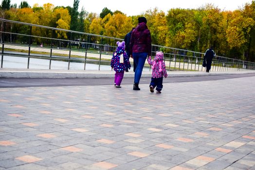 people walk along the pond on a cloudy autumn day