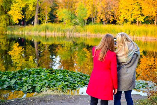 people walk along the pond on a cloudy autumn day