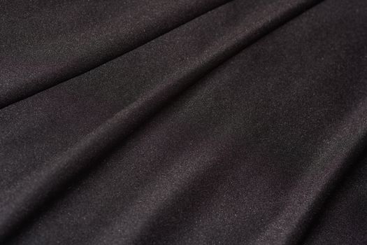 A close-up frame of smooth black satin textile fabric