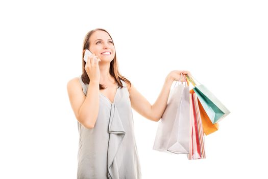 Beautiful smiling young girl holding shopping bags and talking on the mobile phone, isolated on white background.