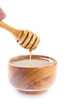 Honey scoop pouring caramel sauce in wooden bowl isolated on white background, Save clipping path.