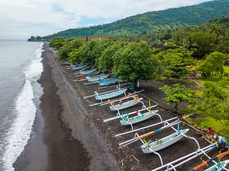 Aerial view of Amed beach in Bali, Indonesia. Traditional fishing boats called jukung on the black sand beach.