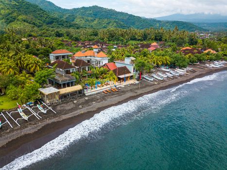 Aerial view of Amed beach in Bali, Indonesia. Traditional fishing boats called jukung on the black sand beach.