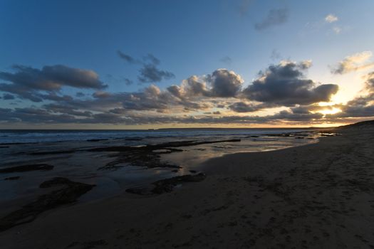 Late afternoon sunset horizon on African south coast beach with clouds and blue night sky, Mossel Bay, South Africa