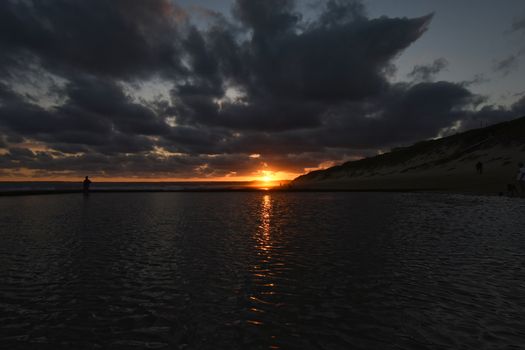 Dusk sunset beach horizon over tidal pool with sun setting in the distance, Mossel Bay, South Africa