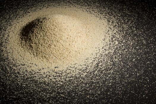 A pile of sand on a black reflective surface