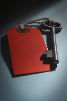 Old key with red tag on a blue table