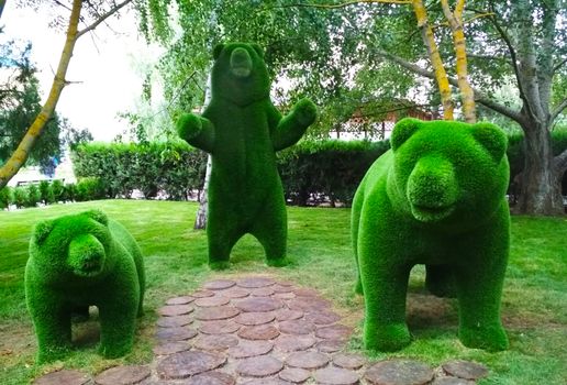 Sculpture of a bear with green cubs in full size in the Park.