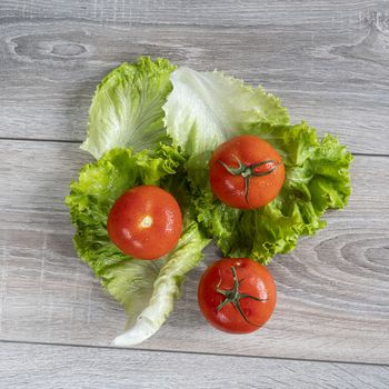 tomatoes on some salad leaves on a wooden table