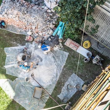 Top view of authentic builder men working with shovel during concrete cement solution mortar preparation in mixer at construction site.