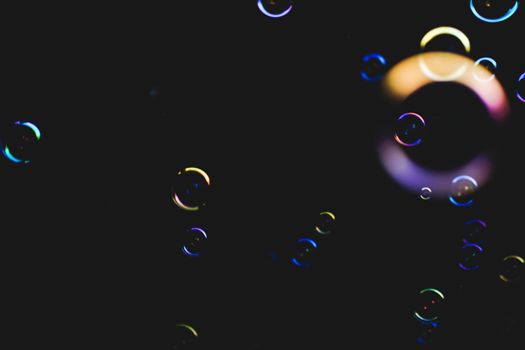 Colorful soap bubbles flying over darck background, shallow depth of field