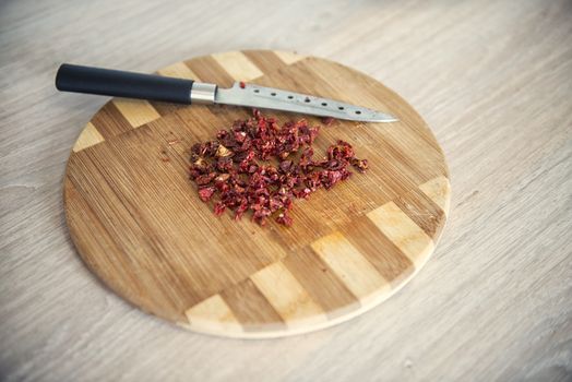 Dry tomatoes finely chopped on a wooden cutting board