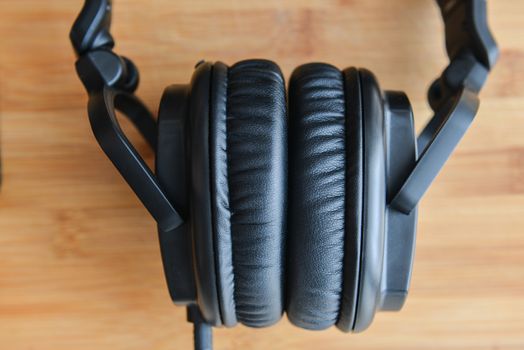 Black headphones on wooden background.