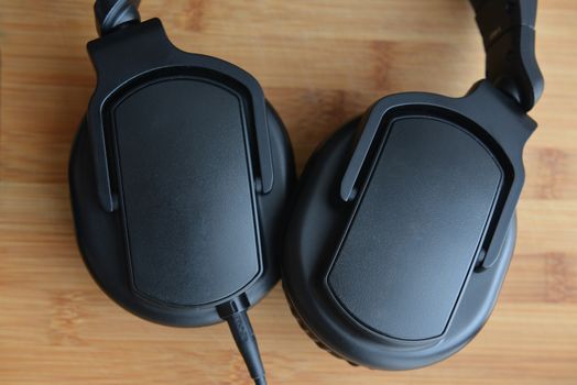 Black headphones on wooden background.