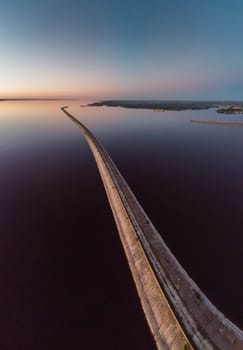 Aerial view of the curve of the road through the reservoir in front of the hydroelectric station. Leaving road to the distance