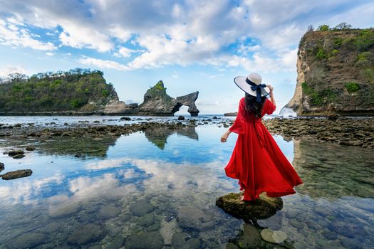 Woman standing on the rock at Atuh beach, Nusa penida island in Bali, Indonesia.