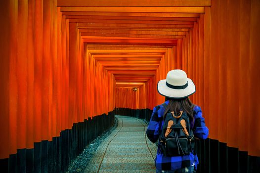 Woman traveler with backpack at fushimi inari taisha shrine in Kyoto, Japan.