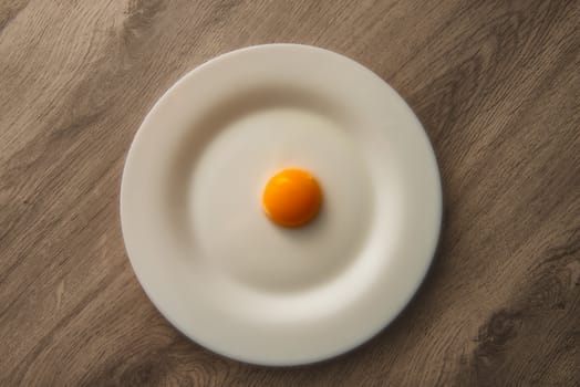 egg yolk on white plate and wooden table