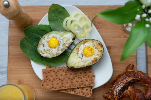 Eggs baked in avocado on plate with onion, juicy and pretzel