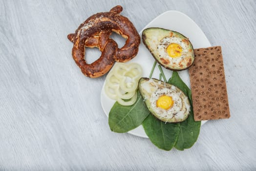 Eggs baked in avocado on plate. Wooden table