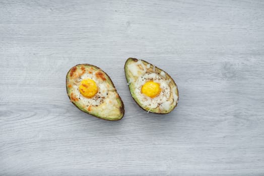 Two eggs baked in avocado on wooden table