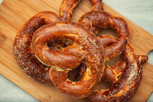 Freshly baked homemade soft pretzel with salt on wooden cutting board.