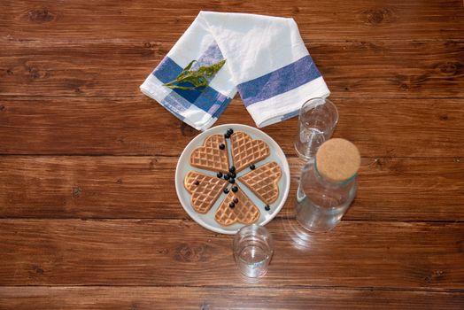 an empty bottle, two glasses and wafers on a plate. Wooden background