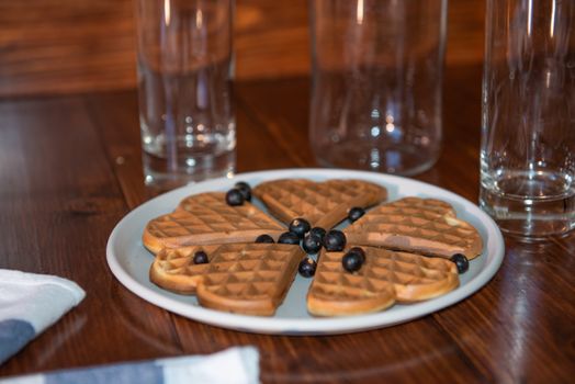 an empty bottle, two glasses and wafers on a plate. Wooden background