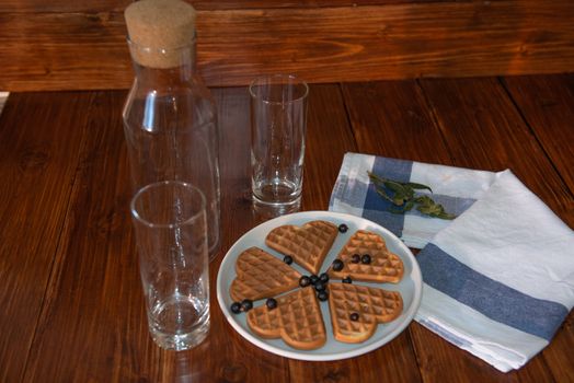 an empty bottle, two glasses and wafers on a plate. Wooden background