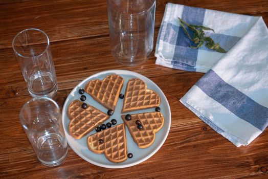 an empty bottle, two glasses and wafers on a plate. Wooden background