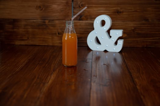 a vintage bottle of freshly squeezed juice on a wooden background and a glowing ampersand.