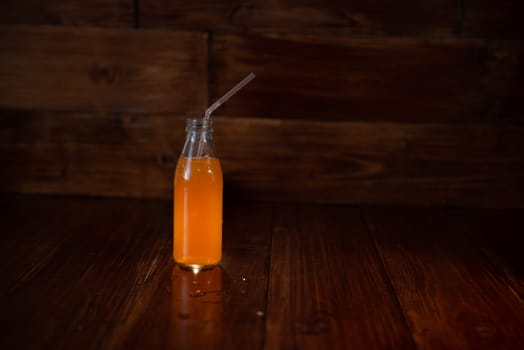 vintage bottle with juice and straw on wooden background.