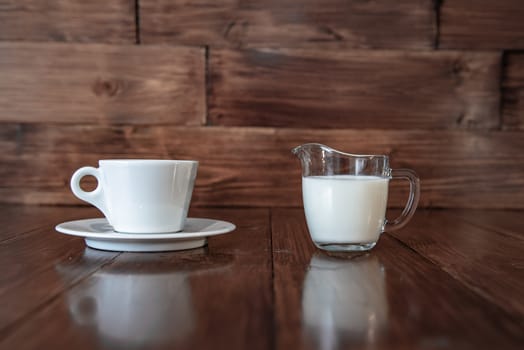 milk in glass milk jug on wooden background
