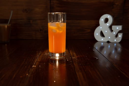 a glass of freshly squeezed juice on a wooden background and a glowing ampersand.