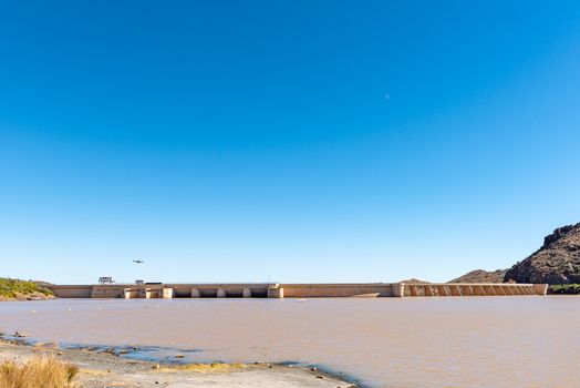 The Vanderkloof Dam in the Orange River (Gariep River) as seen from Vanderkloof town. A bird and the moon are visible
