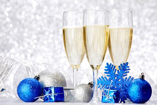 Glasses of champagne and decorative christmas balls on glitter background