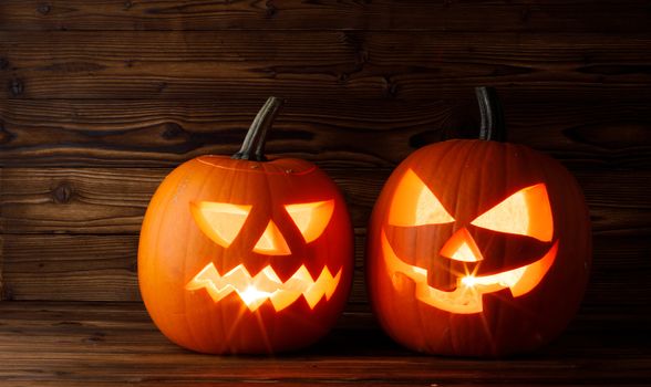 Halloween pumpkins head jack o lantern with candle inside on wooden background