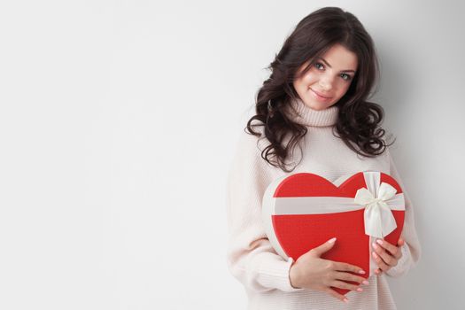 Young girl with red heart-shaped gift box on white background