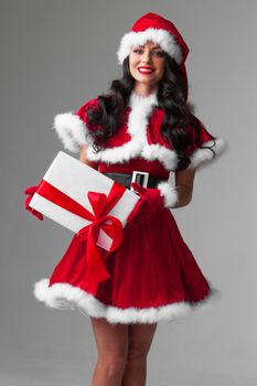 Woman in red Santa Claus outfit holding christmas gift box