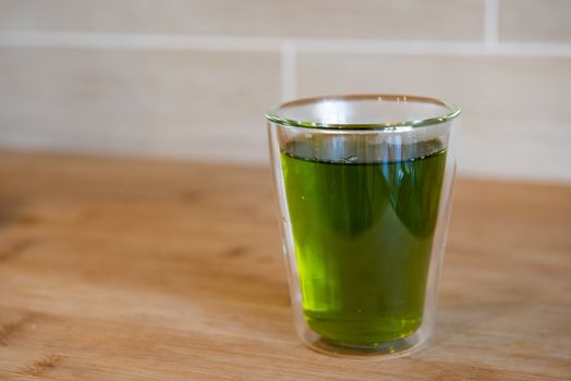 Green Tea cup and glass jugs or jars on the wooden table.