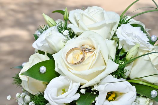 Wedding rings on a bouquet of white flowers.