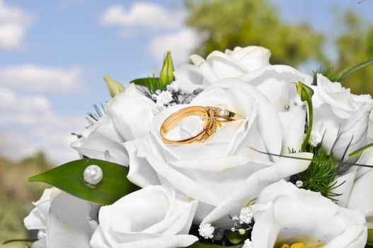 Wedding rings on a bouquet of white flowers.