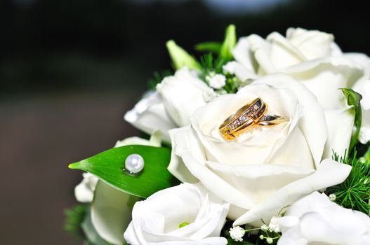 Wedding rings on a bouquet of white flowers.