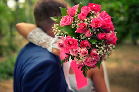nice wedding bouquet in bride's hand. Kiss across bouquet