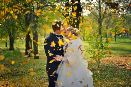 a kiss of a newly-married couple in an autumn park.