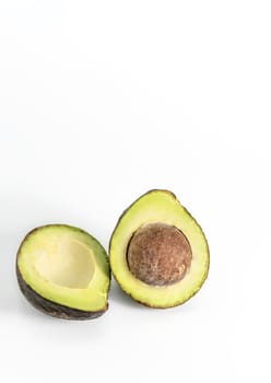 Whole and cut in half avocado fruit on white background