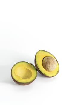 Whole and cut in half avocado fruit on white background