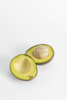 Whole and cut in half avocado fruit on white background