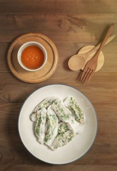 Top view Vietnamese Steamed Rice Dumplings served with spicy chili sauce over wooden table