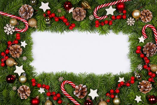 Christmas Border frame of tree branches on white background with copy space isolated, red and golden decor, berries, stars, cones